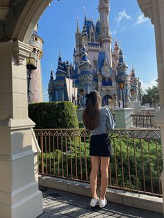 a woman standing in front of a castle looking out at the grounds and walkways