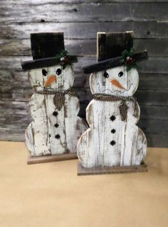 two wooden snowmen with hats and bows on their heads