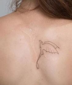 the back of a woman's shoulder with a small tattoo design on her left shoulder