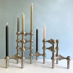 four candles are lined up next to each other on a white counter top with blue walls in the background