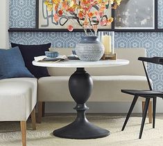 a living room with two chairs and a table in front of a wallpapered background