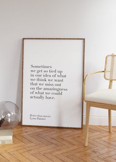 a white framed poster sitting on top of a hard wood floor next to a chair