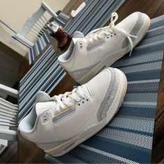 a pair of white sneakers sitting on top of a blue rug