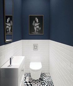 a white toilet sitting next to a sink in a bathroom under two pictures on the wall