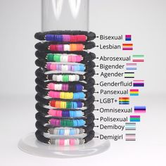 a stack of bracelets sitting on top of a white table next to a glass