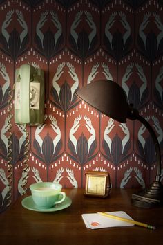 a desk with a phone, cup and saucer on it next to a wallpaper