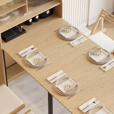 a wooden table topped with white plates and silverware