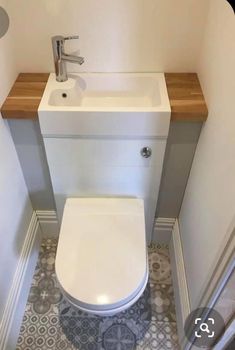 a white toilet sitting in a bathroom next to a wooden counter top under a faucet