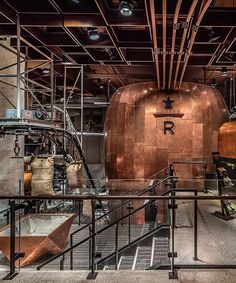 the inside of a building with metal pipes and large copper pots on it's sides