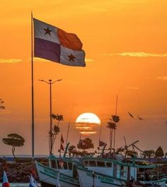 the sun is setting over boats in the water