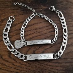 two personalized bracelets on a wooden table with the names of two people engraved on them