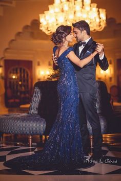 a man in a tuxedo and a woman in a blue dress dance together