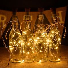 four glass bottles with fairy lights in them