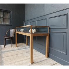 a wooden table sitting on top of a hard wood floor next to a gray wall