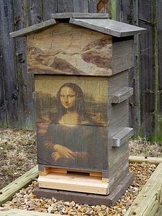 a beehive with a painting on it in front of a fenced area