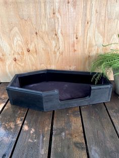 a wooden crate with a plant in it sitting on a wood deck next to a wall