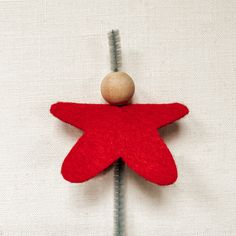 a red felt star ornament with a wooden ball on top