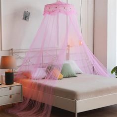 a bed with a pink mosquito net on top of it's headboard and foot board