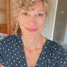 a close up of a person wearing a polka dot shirt and smiling at the camera