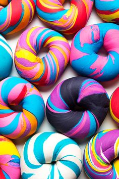 colorful doughnuts with different colors and designs on them are displayed in this image