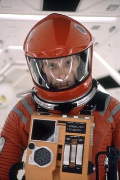 a man in an orange space suit holding a radio