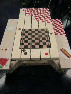 a table made out of pieces of wood with chess board on top and checkered floor