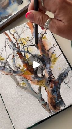 a person is painting a tree with watercolors