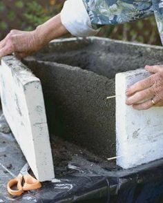 an older man is working on cement with his hands and nails in the concrete box