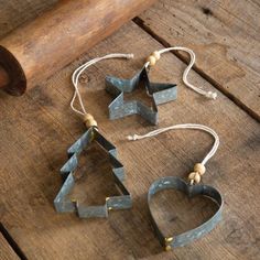 three ornaments made out of metal are sitting on a wooden table next to a hammer