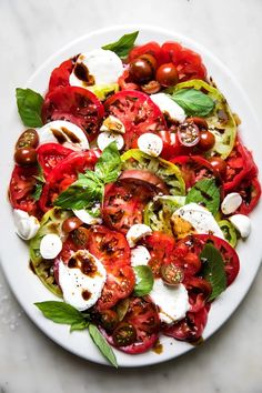 a white plate topped with lots of tomatoes and mozzarella