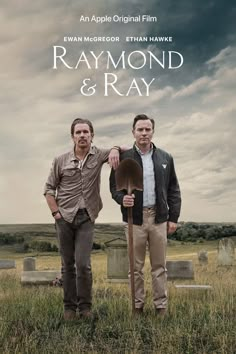 two men standing next to each other on top of a grass covered field in front of tombstones