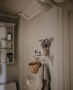 a white toilet sitting next to a shelf with a basket on it's side