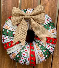 a christmas wreath hanging on the side of a wooden door with burlocks and ribbons