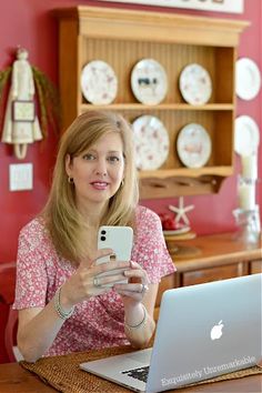 a woman sitting at a table with a laptop and cell phone in front of her