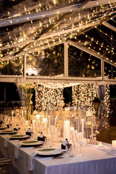 the table is set with candles and place settings for an elegant wedding reception at night