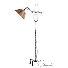 an iron and wood floor lamp with a wooden shade on the top, standing against a white background