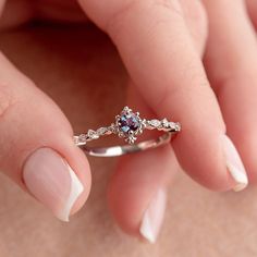 a woman's hand holding a ring with a white opal and diamonds on it