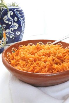 a brown bowl filled with rice next to two blue vases on a white table