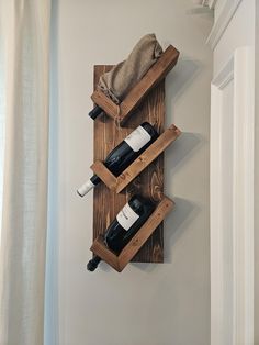 a wooden wine rack with two bottles on it and a towel hanging from the wall