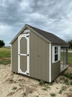 a small shed sitting in the middle of a field with grass and dirt around it