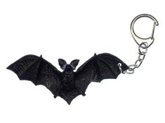 a black bat shaped keychain hanging from a metal hook on a white background