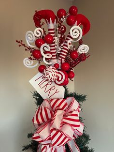 a red and white christmas tree with candy canes on it's top,