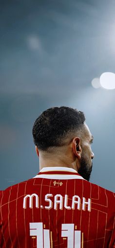 a man in a red jersey looking up at the sky with his head tilted back