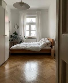 an empty bedroom with a bed and wooden floors