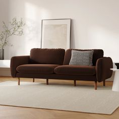 a brown couch sitting on top of a wooden floor next to a white table and chair