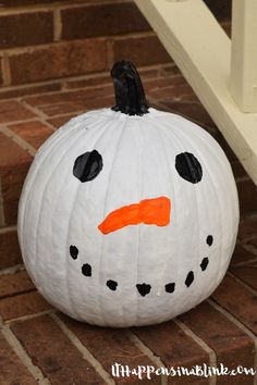 a white pumpkin with a black nose and orange nose painted on it's face