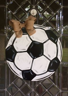 a black and white soccer ball with a bow on it's head hanging from a chain link fence