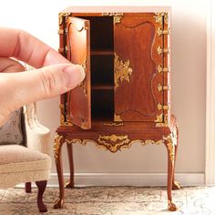 a hand is pointing at a miniature cabinet