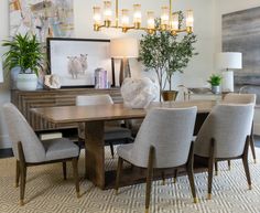 the dining room table is surrounded by beige chairs and gold chandeliers, along with art on the wall