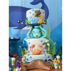 a blue and white cake with an octopus on top is surrounded by sea animals, under the water